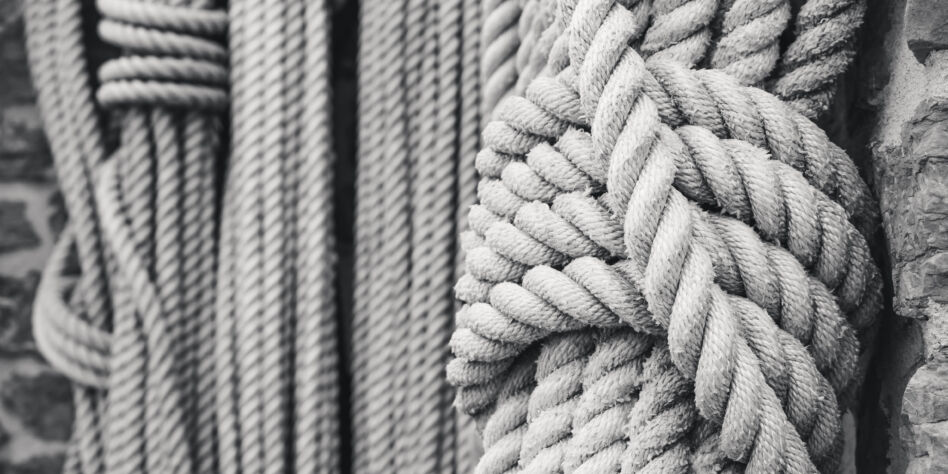 A tied rope hangs among other ropes of different thicknesses