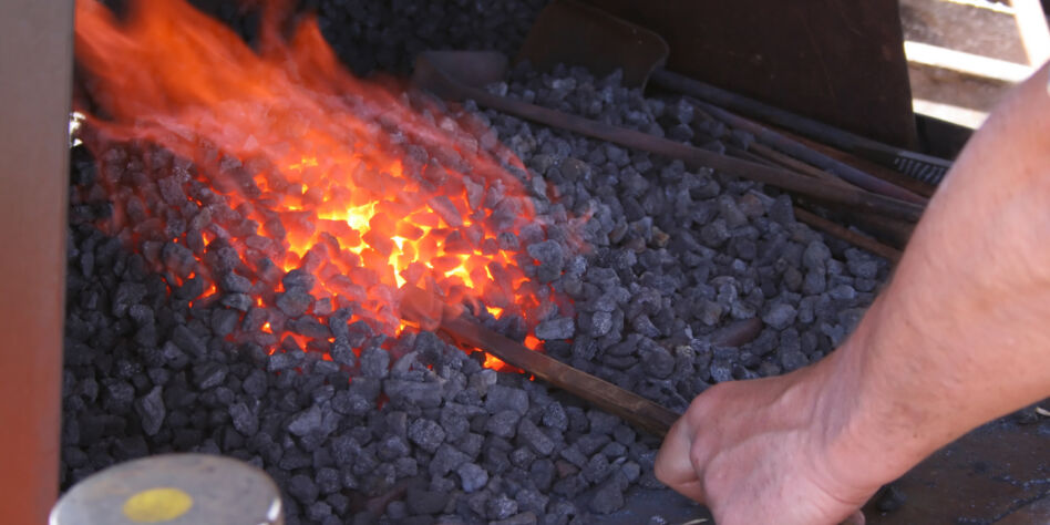 Blacksmith heating iron in an open furnace