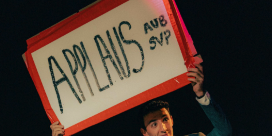 Man steekt bord in lucht met "Applaus" op geschreven